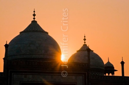 Sun rays from behind domes of the Taj Mahal