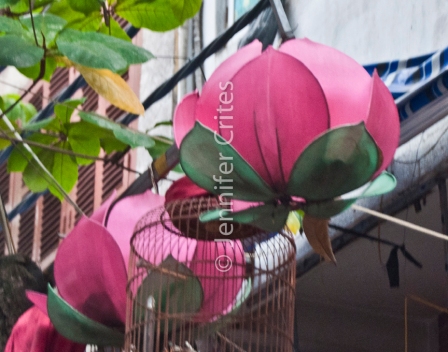 giant man-made lotus blossoms hanging over a street in Hanoi